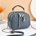 Detail view of grey quilted crossbody bag with multi-layer zippers and bear pendant - Gray