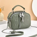 Detail of pea green quilted crossbody bag with silver bear charm and tassel on double zipper - Green