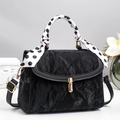Close-up of black pleated texture bag with golden lock and polka dot scarf handle - Black