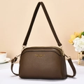 Brown litchi grain leather crossbody bag with gold hardware on a lifestyle background - Brown