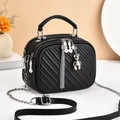 Detail of black quilted crossbody bag with silver chain strap and bear charm pendant - Black