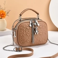Detail of heart quilting texture, bear charm, and tassel on camel crossbody bag - Khaki