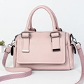 Close-up of light pink Boston bag with pebble leather texture and woven shoulder strap - Pink