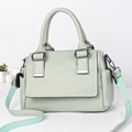 Detail of mint green leather bag showing wide fabric strap and textured grain surface - Green