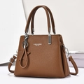 Brown litchi grain leather handbag with top handles and star pendant on a clean backdrop - Earthy Yellow