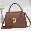 Detail of dark brown lychee leather handbag featuring a stylish gold wavy metal buckle - Coffee