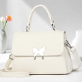 Close-up of litchi leather handbag with silver butterfly buckle and reinforced handle - Off White