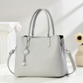 Detail view of light grey pebble-grain handbag with elegant pearl tassel and silver charms - Gray