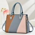 Close-up of tricolor tote bag with woven texture, blue handles, and gold-tone hardware - Blue