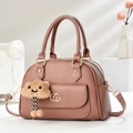 Close-up of lychee grain leather handbag with gold buckles and fluffy cloud charm - Pink