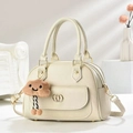 Detail of minimalist cream leather satchel featuring gold hardware and a cute plush charm - Off-white