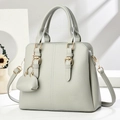 Close-up of a light grey lychee leather handbag with gold buckles and heart charm - Gray
