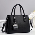 Sac à main noir texturé avec pendentif argenté sur fond gris et fleurs blanches - Noir