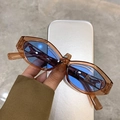 Primer plano de gafas de sol ovaladas de leopardo con lentes azules en la mano - Montura Té Claro Lentes Azules