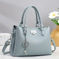 Detailed view of light blue lychee pattern leather handbag with silver turn-lock and pearl charm - Blue