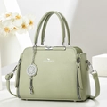 Borsa a mano in pelle verde salvia con logo argento e ciondolo su piedistallo bianco - Verde