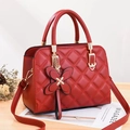 Sac à main matelassé rouge avec pendentif papillon et chaîne dorée sur table en bois - Bordeaux