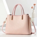 Chic pink woven tote bag with dual handles and gold hardware in minimalist studio setting - Pink