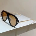 Detail der übergroßen schwarzen Sonnenbrille mit braunen Gläsern und goldenen Akzenten - Schwarzer Rahmen Tee Gläser