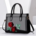 Elegant black patent leather handbag with red 3D rose decor and gold hardware details - Black