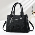 Retro black tote bag with circular handles and clover charm against a sunlit white wall - Black