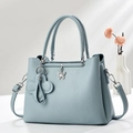 Close-up of light blue lychee pattern handbag with silver butterfly pendant and floral charm - Blue