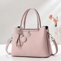 Detailed view of pink lychee grain leather tote with silver butterfly and flower charms - Pink