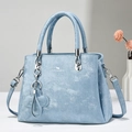 Detalle del bolso tote azul claro con herrajes plateados y un colgante de trébol - Azul