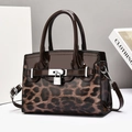 Close-up of leopard print and glossy patent leather luxury handbag with gold metal lock - Coffee