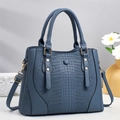 Borsa tote blu con motivo a coccodrillo, doppi manici e tracolla su una scrivania - Blu
