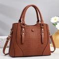 Détail du sac cabas marron en cuir de crocodile avec clous dorés et bandoulière - Jaune Terre