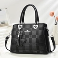 Bolso tote negro con diseño de cuadros, asas y colgante de trébol en superficie blanca - Negro