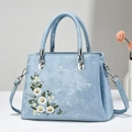 Dettaglio borsa a mano azzurra con ricamo floreale e anelli in metallo color argento - Blu