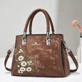 Close-up of brown suede tote bag featuring delicate white flower embroidery and silver hardware - Coffee
