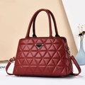 Dettaglio borsa rossa trapuntata con logo triangolare in metallo e doppi manici corti - Rosso