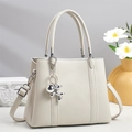 Elegant beige lychee texture tote bag with a metal balloon dog charm on a decorative desk - Off-white