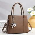 Brown lychee-grain leather tote bag detail with adjustable strap and balloon dog charm - Brown