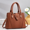 Braune Handtasche mit Krokodilprägung und goldenen Beschlägen in minimalistischer Szene - Erdgelb