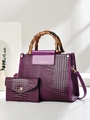 Detail of purple crocodile-patterned bag with bamboo handle and matching small clutch - Purple