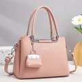 Detail of pink lychee leather handbag with silver hardware and mini decorative charm - Pink