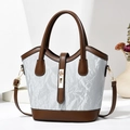 Detail of a light blue marble-textured bucket bag with brown leather handles and gold lock - Gray