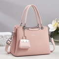 Detail of pink crossbody bag with woven texture, metal logo, and mini bag charm - Pink