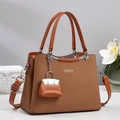 Detail of woven brown handbag with BABK & CLASSIC text and mini bag charm accessory - Khaki/Earth Yellow