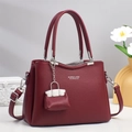 Détail d'un sac à main en cuir rouge foncé avec finitions argentées et breloque - Rouge