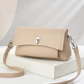 Beige pebble leather crossbody bag with silver twist lock on a minimalist white stone pedestal - 23cm x 8cm x 12cm / Light Khaki