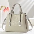 Detail of grey crocodile embossed texture and silver hardware on a leather handbag - Light Gray