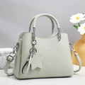 Beige litchi grain tote bag with star pendant, shown from a front angle on a podium - Gray