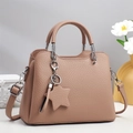 Close-up of pink leather tote bag featuring star charm and elegant tassel detail - Purple