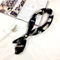 Elegante foulard di seta nera con motivi di piume colorate su un tavolo minimalista - Piuma Nera
