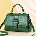 Detail of emerald green crocodile embossed patent leather handbag with gold hardware - Green